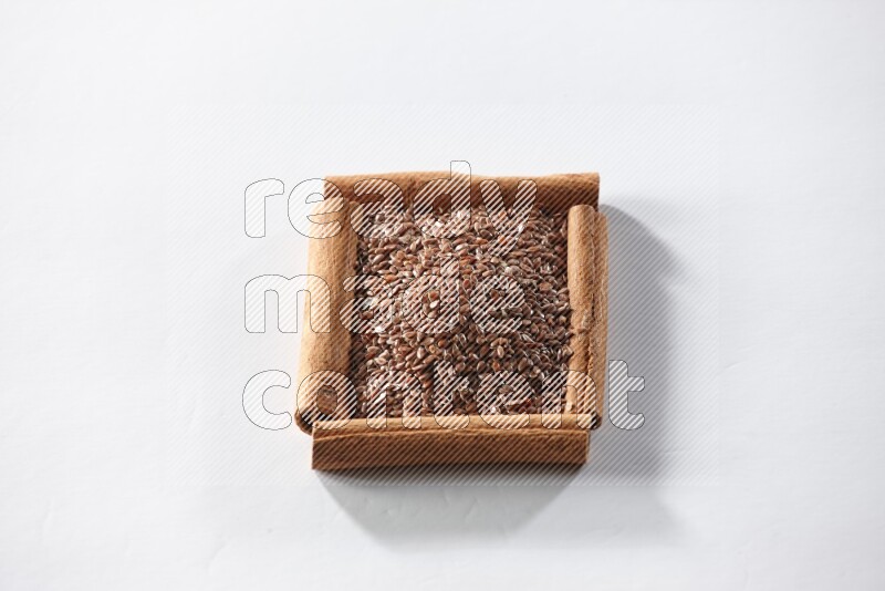 A single square of cinnamon sticks full of flaxseeds on white flooring