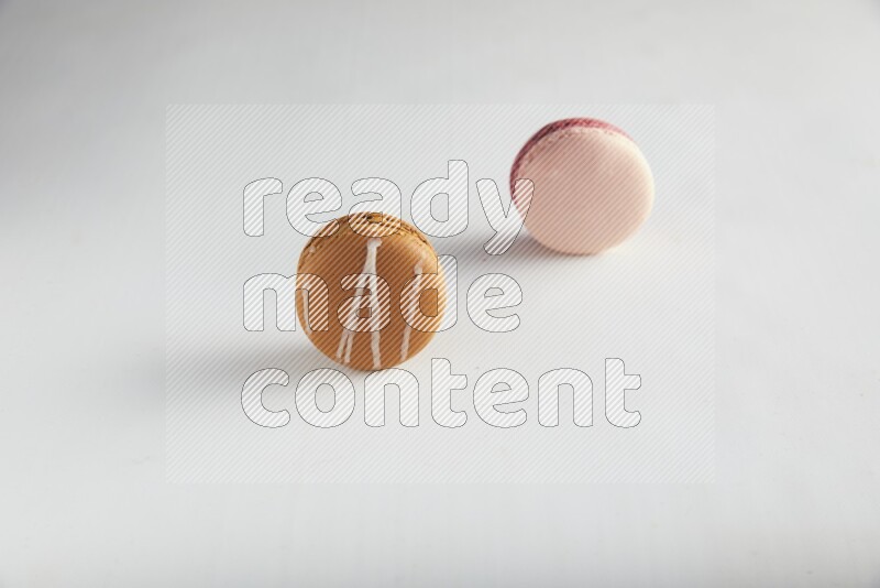 45º Shot of of two assorted Brown Irish Cream, and Pink Litchi Raspberry macarons on white background