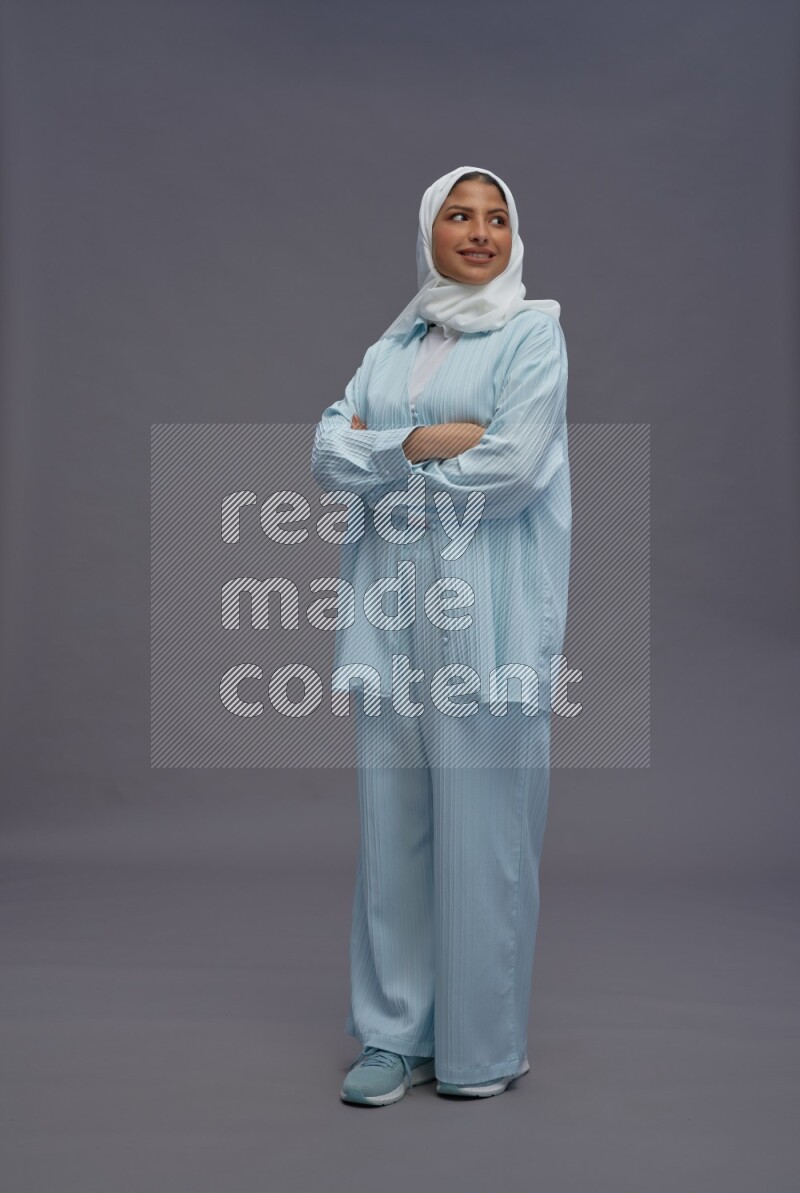 Saudi woman wearing hijab clothes standing with crossed arms on gray background