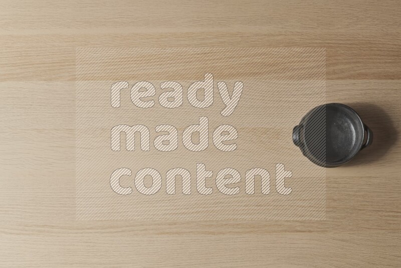 وعاء فخاري أسود على خلفية خشبية فاتحة