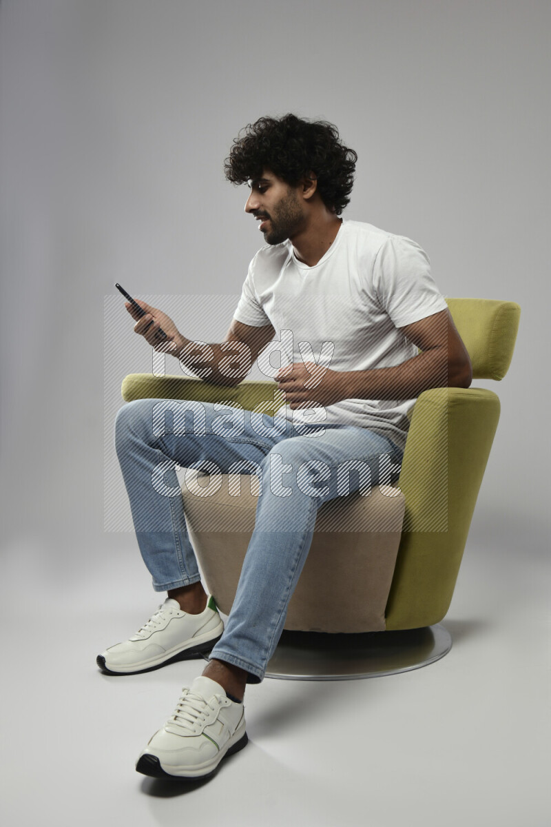 A man wearing casual sitting on a chair talking on the phone on white background