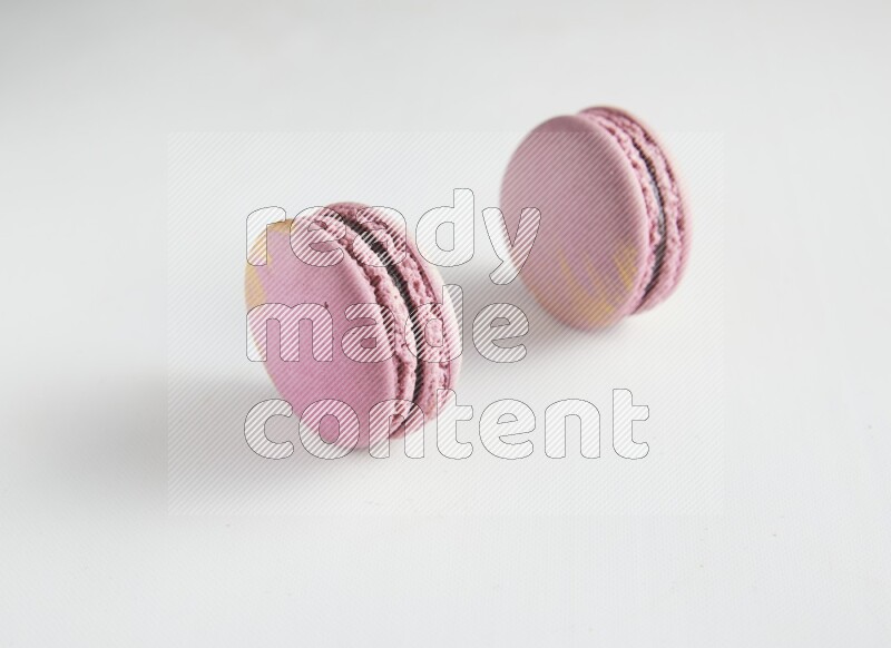 45º Shot of two Purple Strawberry macarons on white background