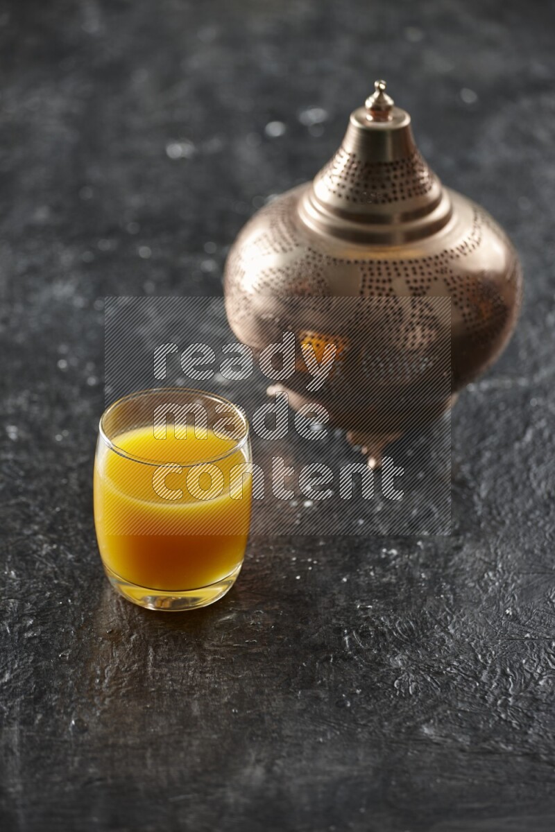 A golden lantern with different drinks, dates, nuts, prayer beads and quran on textured black background