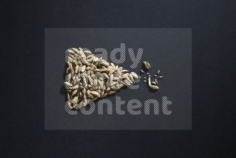 Cardamom in a triangle shape on black flooring