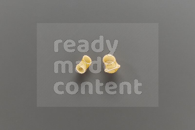 Elbow pasta with other types of pasta on grey background