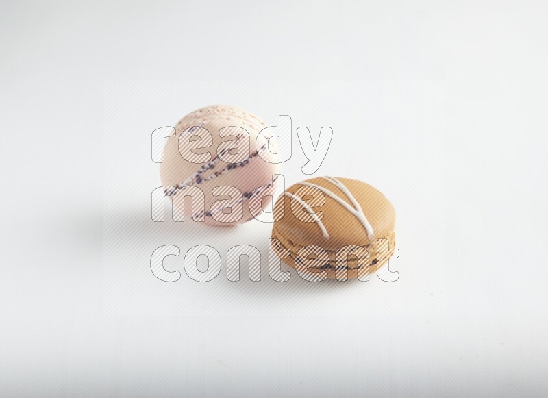 45º Shot of of two assorted Brown Irish Cream, and pink orange blossom macarons on white background