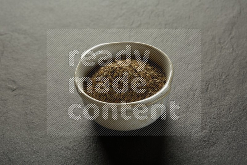 white ceramic round sauce bowl filled with herbs on grey textured countertop