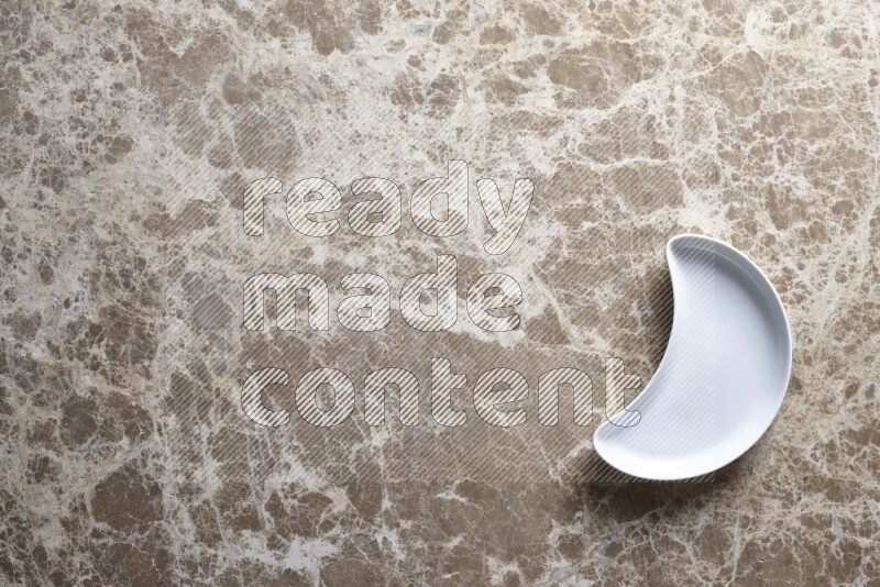 A pottery crescent plate on beige marble background