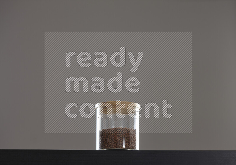 Brown lentils in a glass jar on black background