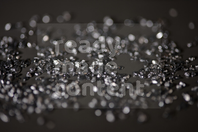 Black shimmering fragments of glass scattered on a black background