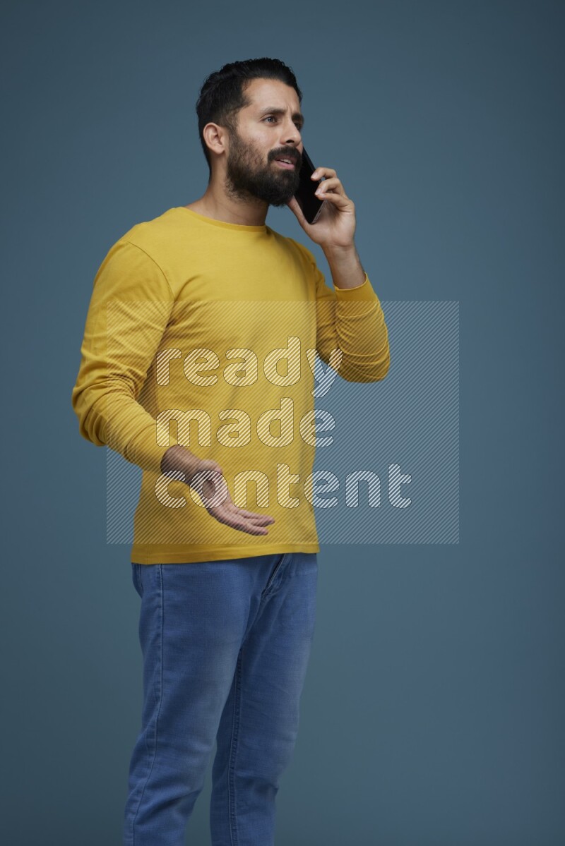 A man having a calling in a blue background wearing a yellow shirt