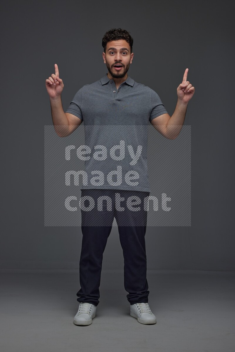 A man wearing casual standing and making multi hand gestures eye level on a gray background
