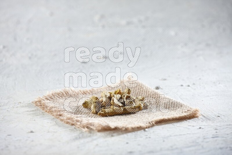 Dried turmeric whole fingers on a piece of burlap on a textured while flooring