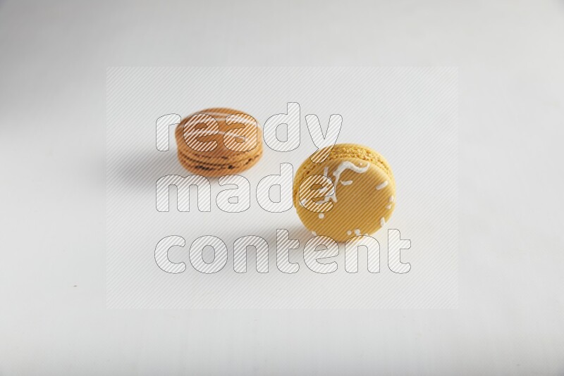45º Shot of of two assorted Brown Irish Cream, and Yellow Piña Colada macarons on white background