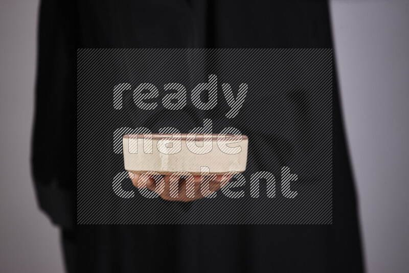 A woman in black abaya holding different pottery essentials in different positions