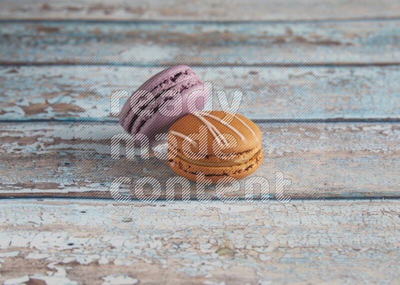 45º Shot of of two assorted Brown Irish Cream, and Purple Blueberry macarons  on light blue background