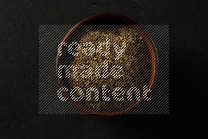 wooden round sauce bowl filled with herbs on grey textured countertop