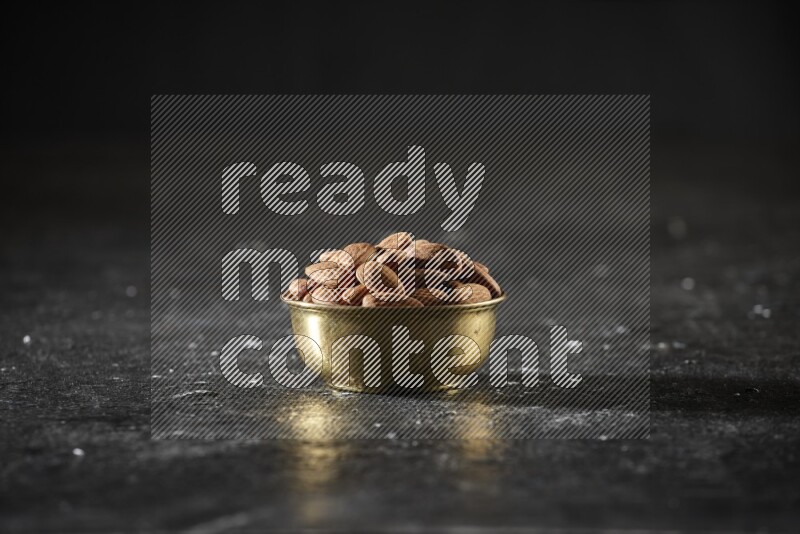 Nuts in a metal bowl in a dark setup