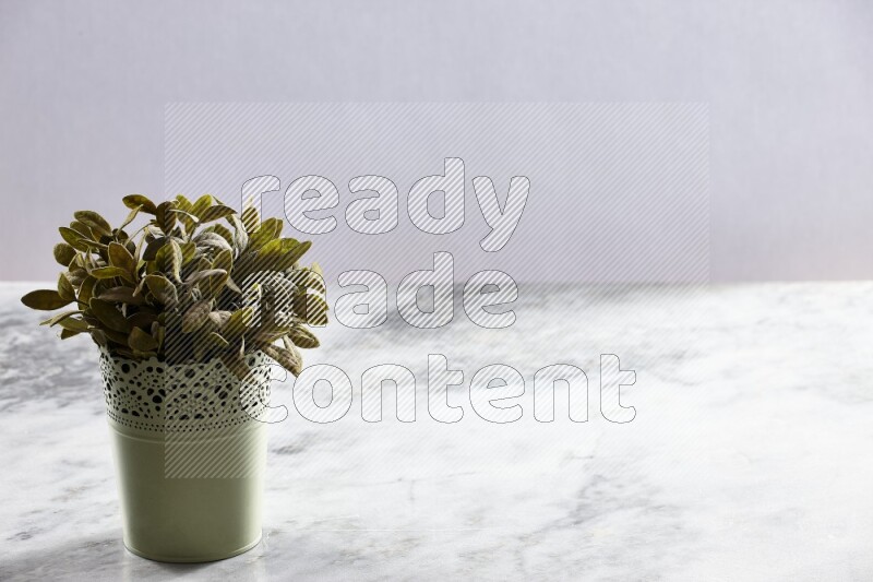 Artificial plant in green decorative pot on grey marble background