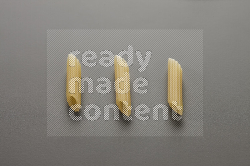 Mini penne pasta on grey background
