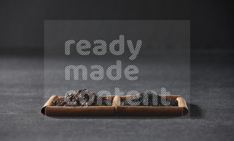 2 squares of cinnamon sticks full of black seeds and cloves on black flooring