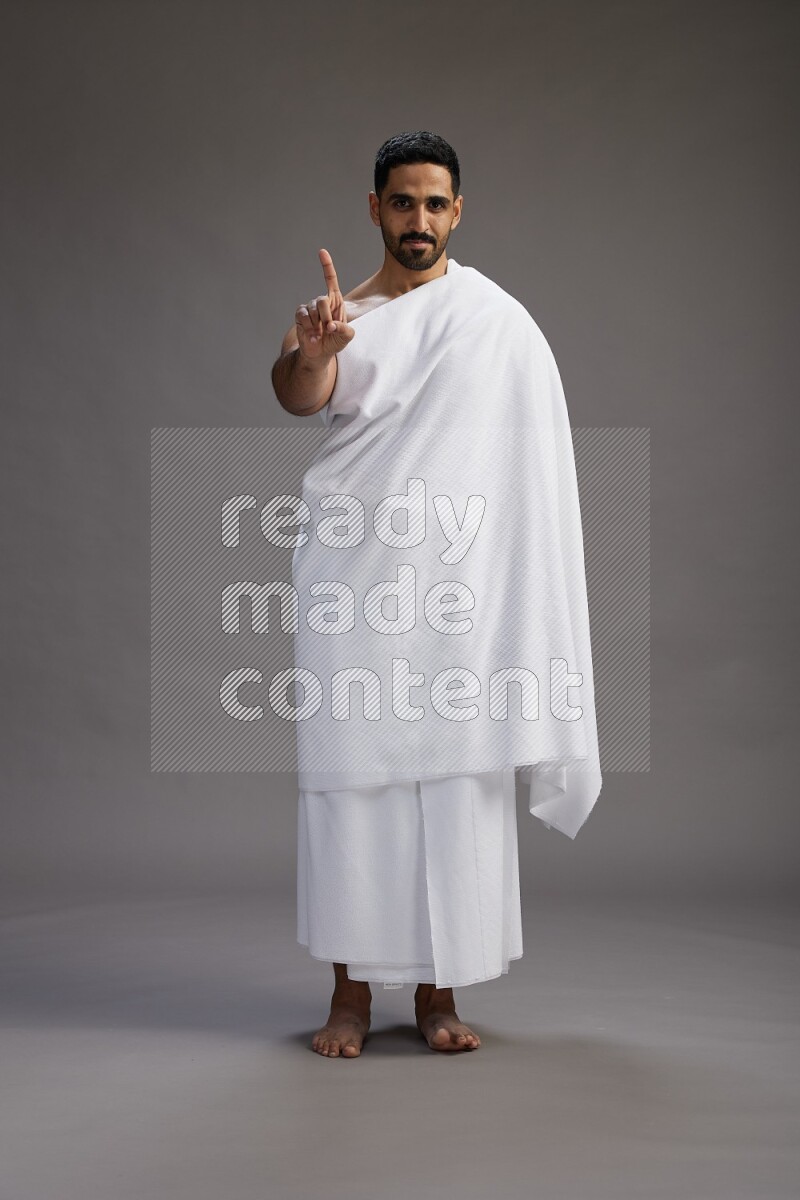 A man wearing Ehram Standing Interacting with the camera on gray background