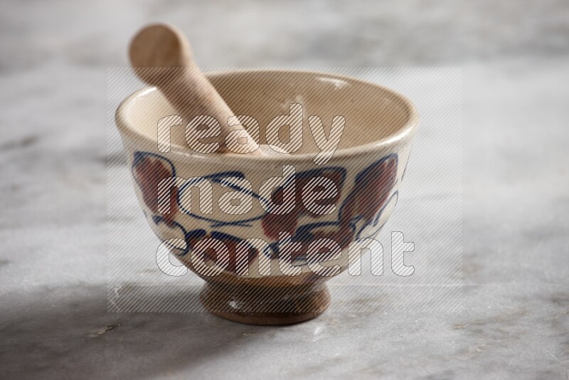 Decorative pottery bowl with wooden honey dipper in it on grey marble background