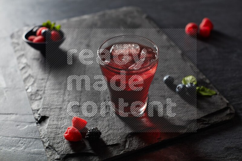 A glass of mixed berries juice on black background