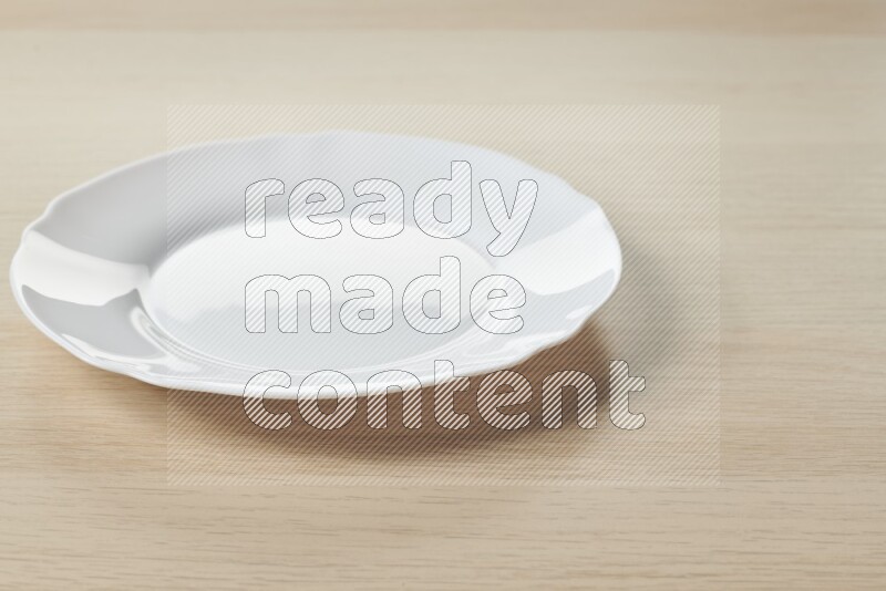 A white ceramic circular plate on light wooden background