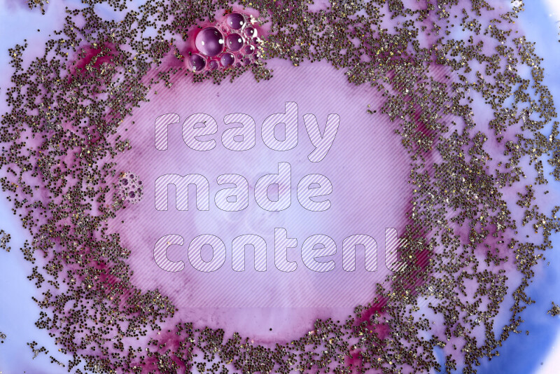 A close-up of sparkling gold glitter scattered on swirling blue and red background