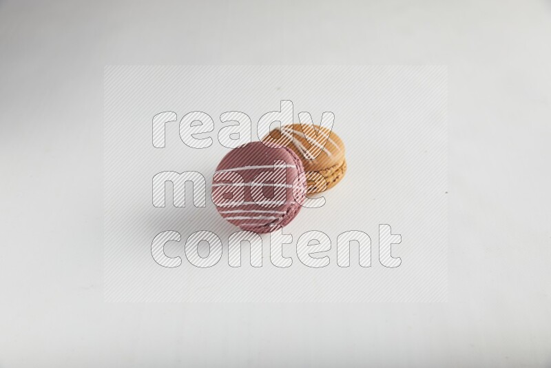 45º Shot of of two assorted Brown Irish Cream, and Red Poppy Flower macarons on white background