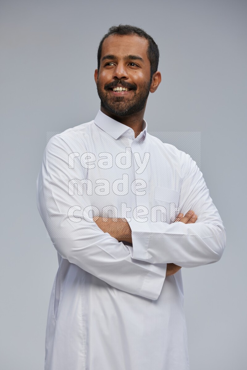 Saudi man wearing Thob standing with crossed arms on Gray background