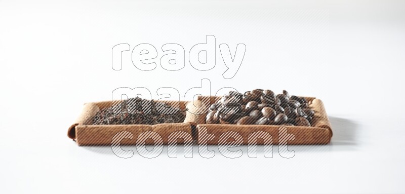 مربعان من أعواد القرفة ممتلئان بحبوب القهوة والشاي الأسود علي خلفية بيضاء