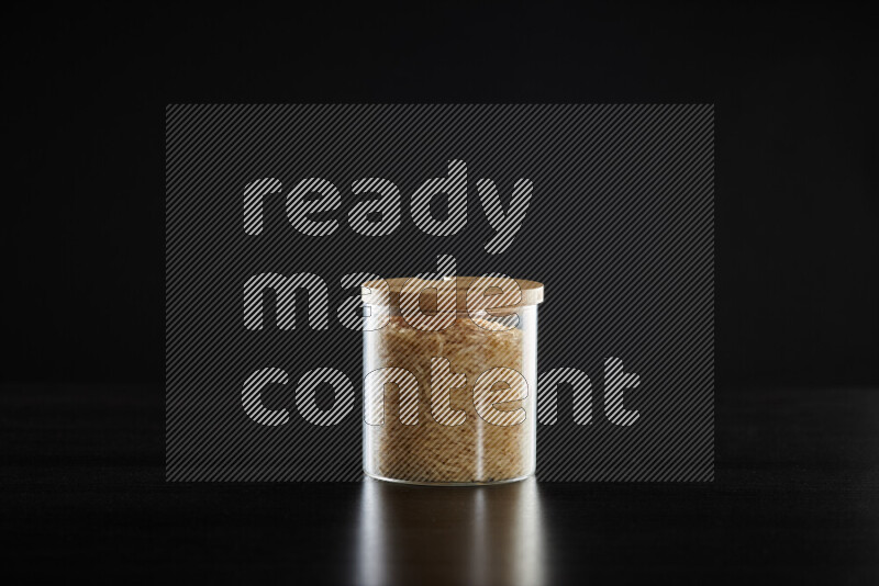 Basmati golden rice in a glass jar on black background