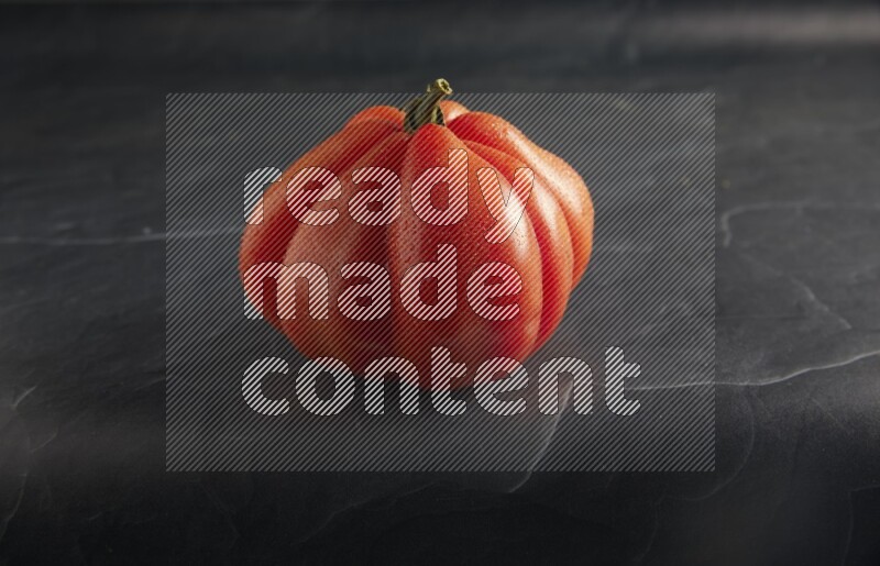 45 degree single heirloom tomato on a textured black slate background