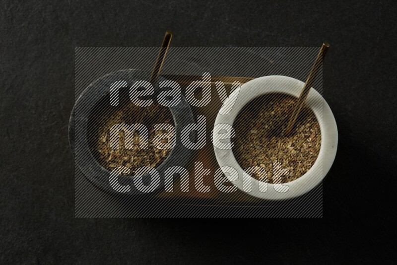 black and white round marble containers filled with herbs on gray textured countertop