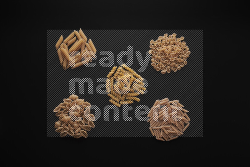 Different pasta types in bunches on black background