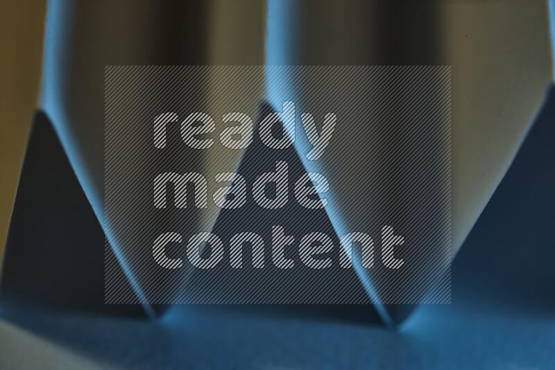 A close-up abstract image showing sharp geometric paper folds in blue gradients and warm tones