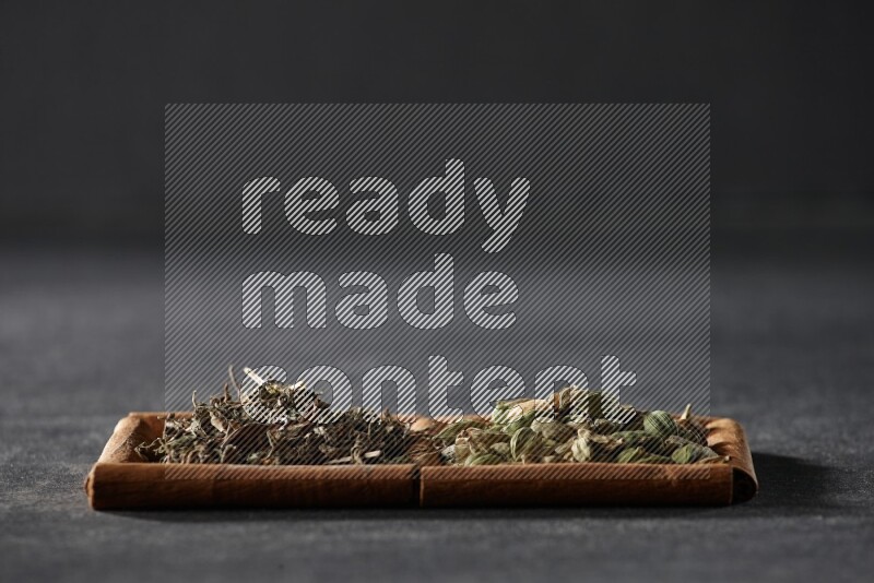 مربعان من أعواد القرفة ممتلئان بحبوب الهيل والريحان المجفف علي خلفية سوداء