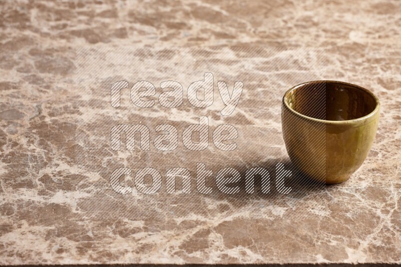 A multicolored pottery cup on beige marble background