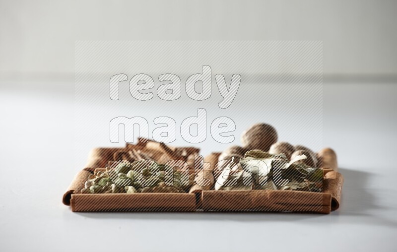 4 squares of cinnamon sticks full of nutmegs, bay laurel leaves, cardamom and cinnamon on white flooring