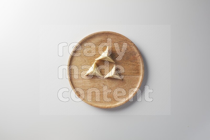 Three Sambosas on a wooden round plate on a white background