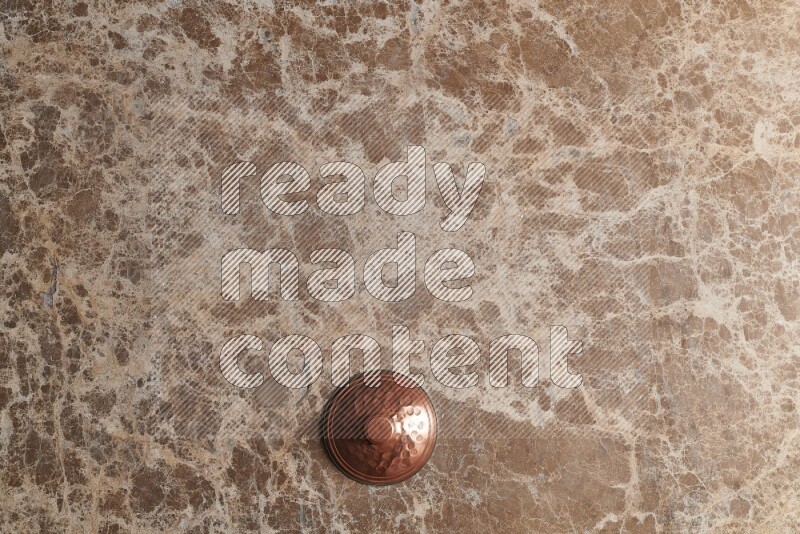 A small copper pot on beige marble background
