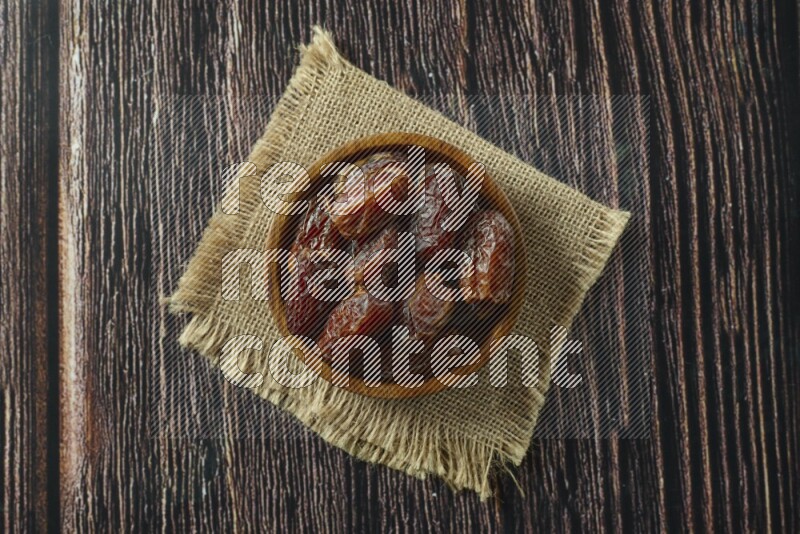 Dates in different bowls (wooden, pottery and glass) on wooden background