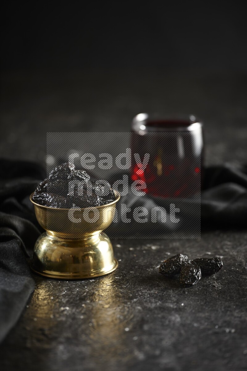 Dried fruits in a metal bowl with Hibiscus and a napkin in a dark setup