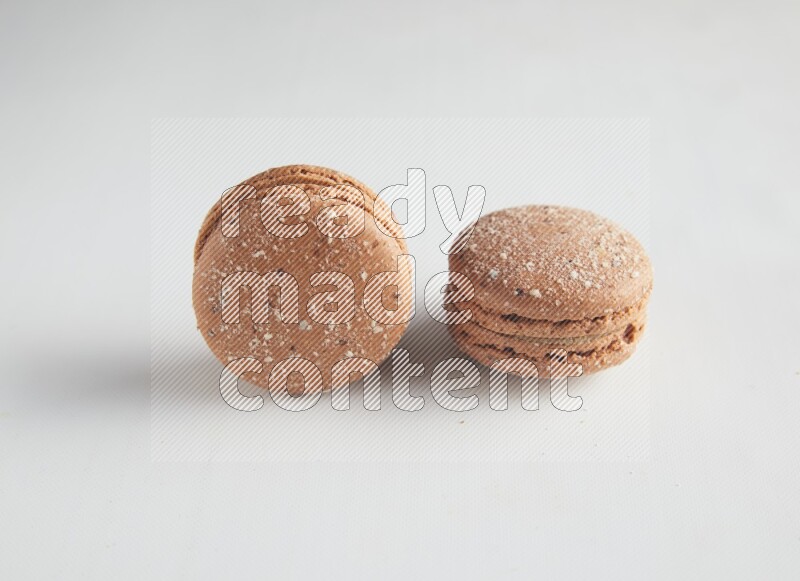 45º Shot of two Brown Hazelnuts macarons on white background
