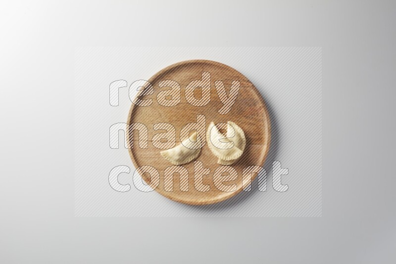 Three Sambosas on a wooden round plate on a white background