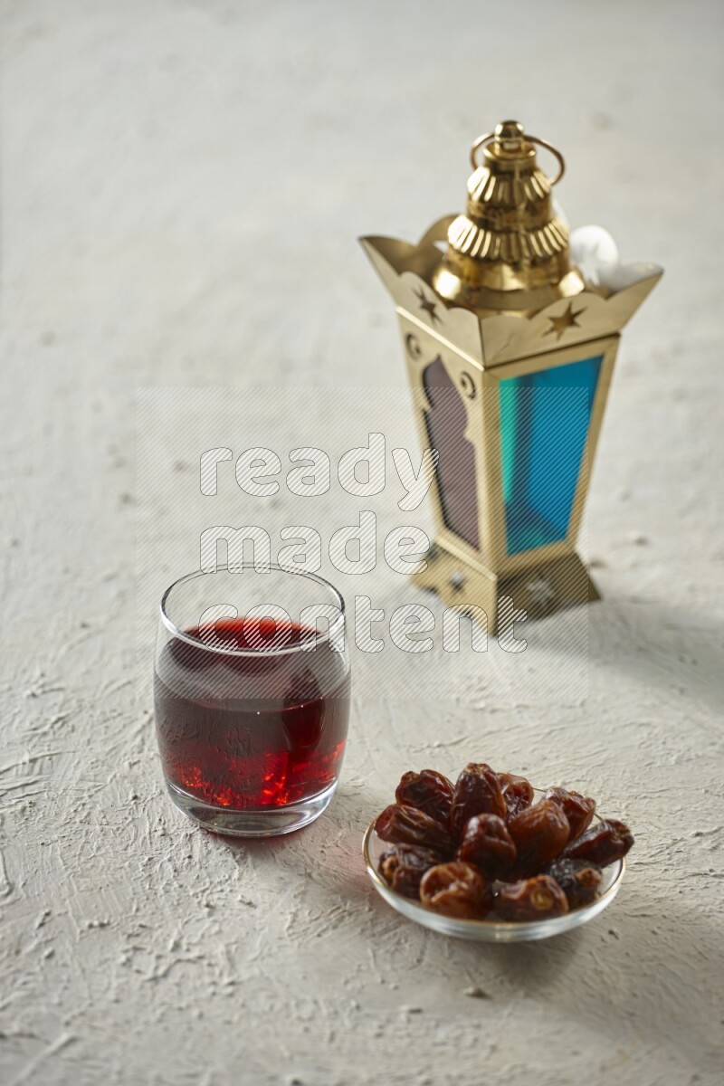 A golden lantern with different drinks, dates, nuts, prayer beads and quran on textured white background