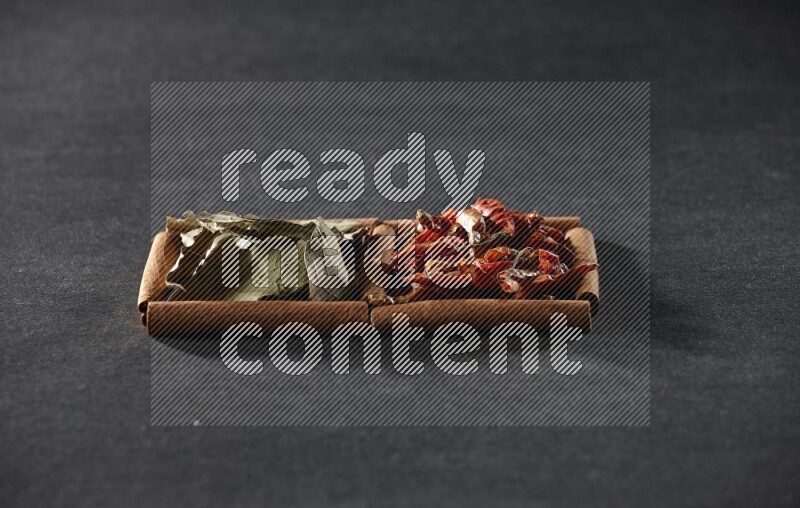 2 squares of cinnamon sticks full of chilis and bay laurel leaves on black flooring