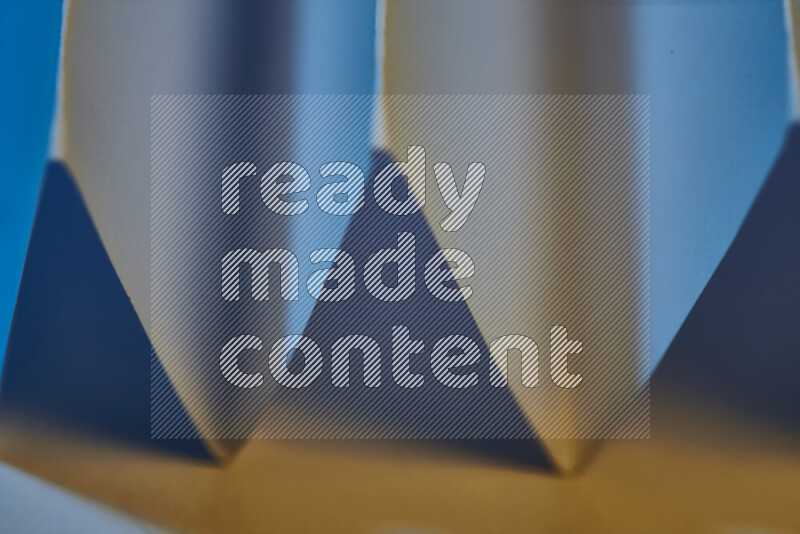 A close-up abstract image showing sharp geometric paper folds in blue gradients and warm tones